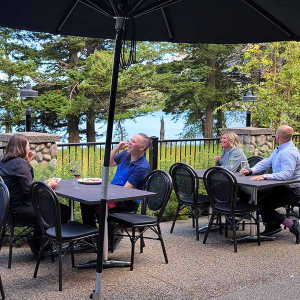 A picture of customers enjoying a lazy afternoon with food and drinks on the Kilmorey Patio on the bank of Waterton Lake.